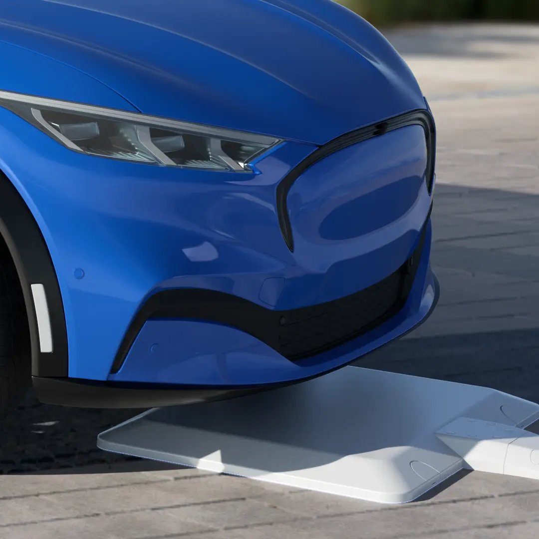 Detailed view of the front of an electric vehicle moving into a wireless EV charging spot