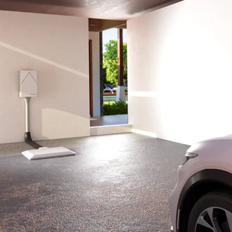 WiTricity Halo (TM) charging system installed in a modern residential garage, bathed in warm sunlight as a vehicle approaches