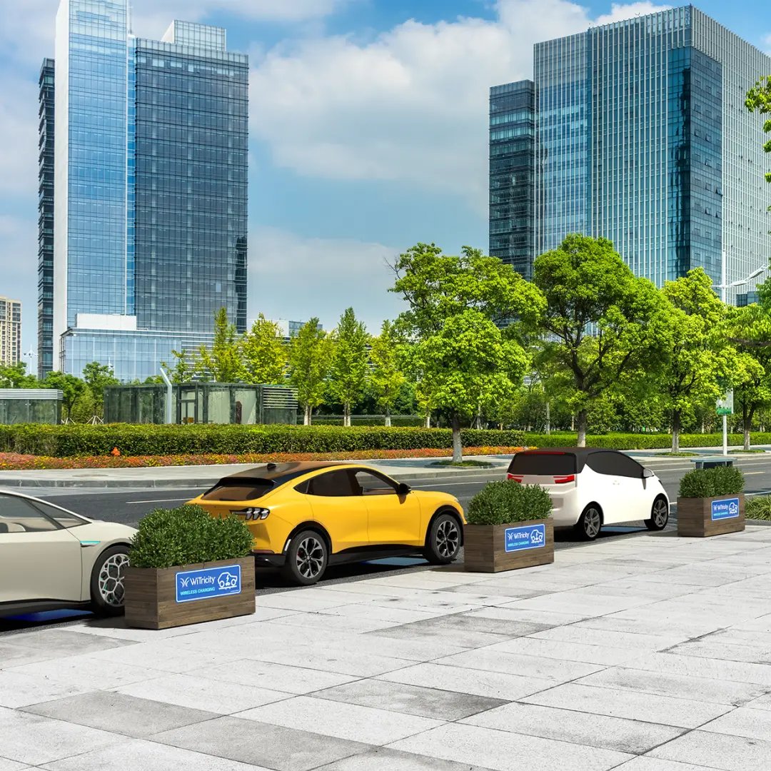 Electric vehicles charge wirelessly along the street of a modern business park