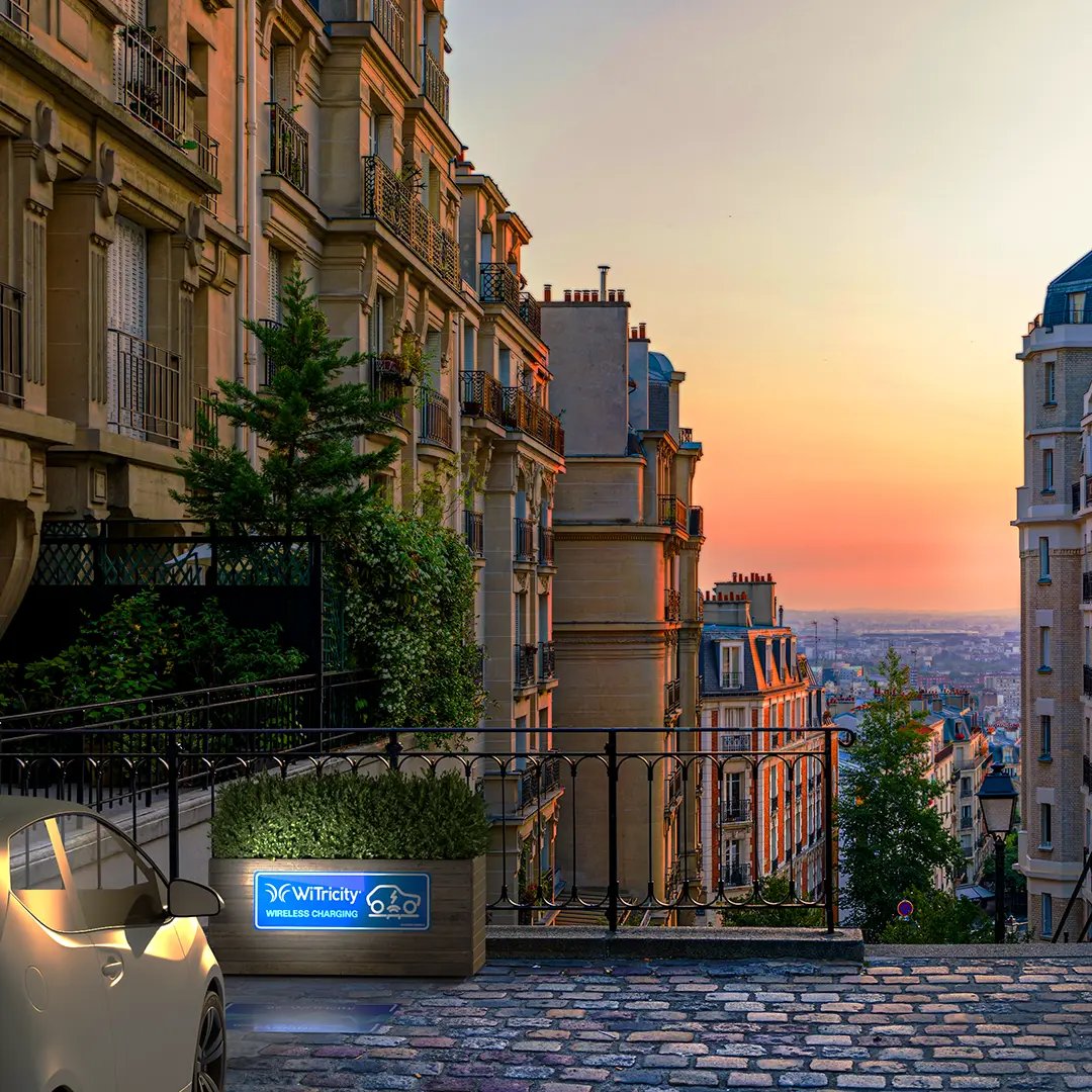 A beautiful vista of a European city at dusk as an electric vehicle charges wirelessly and takes in the view
