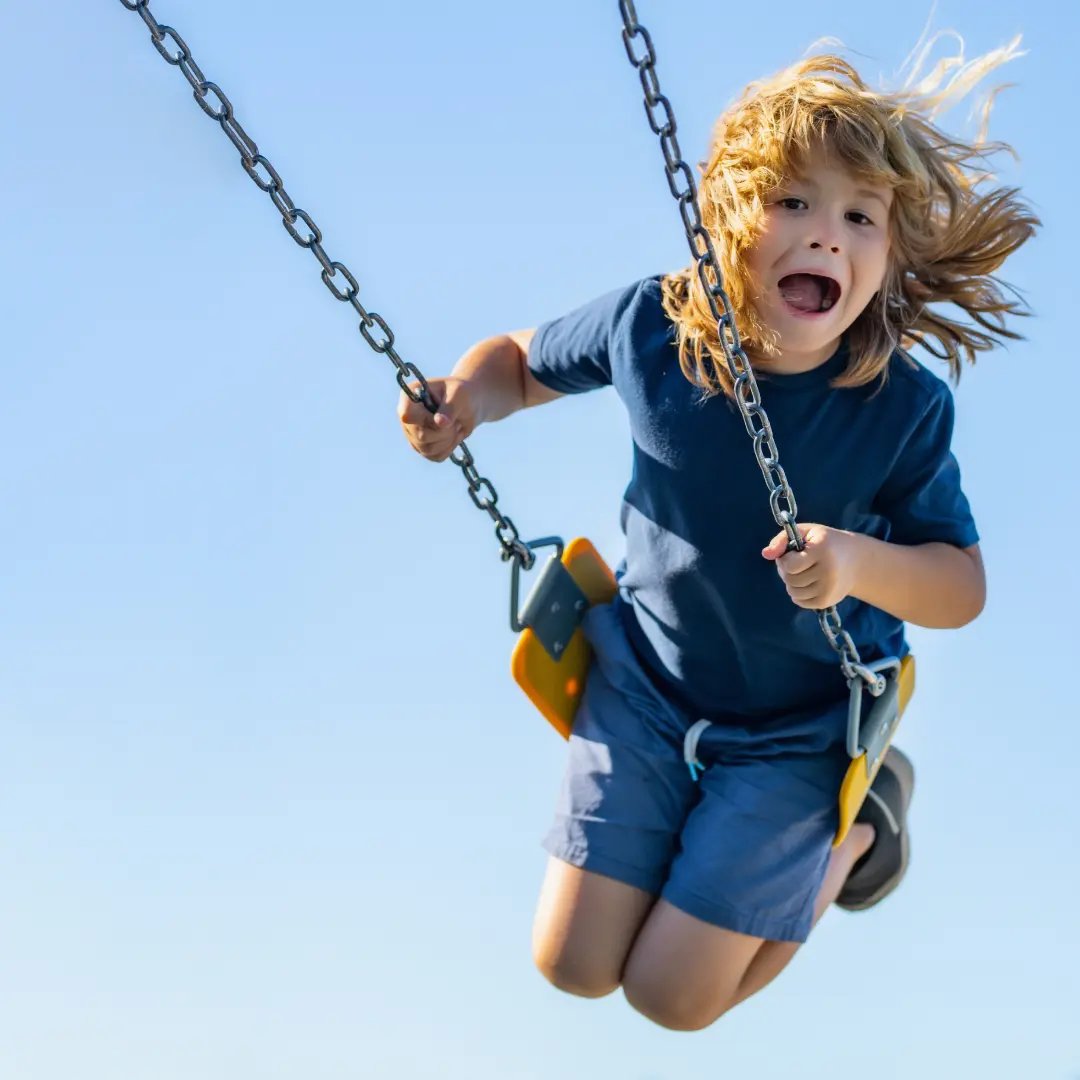 Child swinging very high and smiling