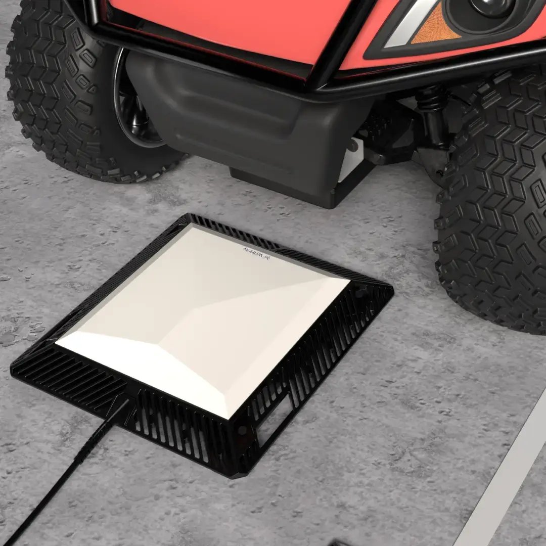 top view of a red golf cart approaching a wireless charger inside a garage